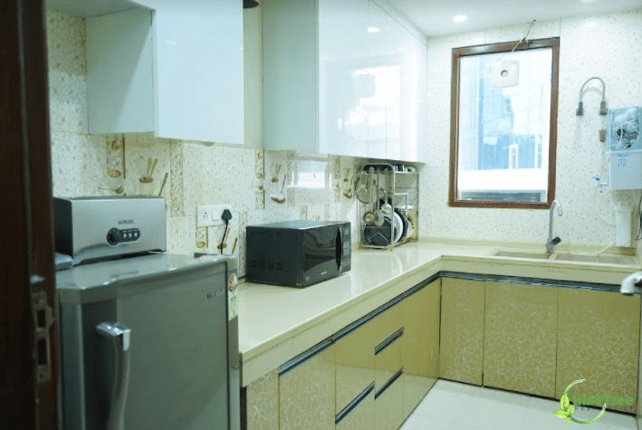 Shared kitchen with a fridge, a microwave and modular cabinets at Lime Tree Hotel Near 32nd Avenue