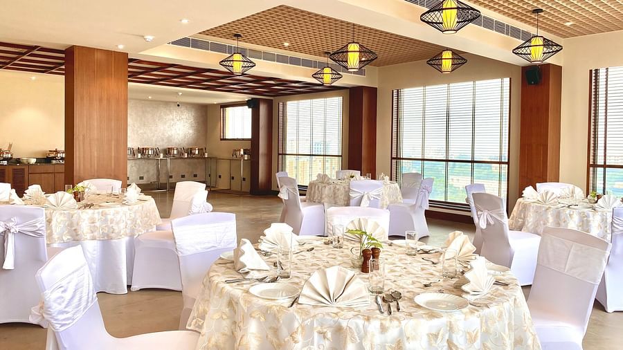 An image of a banquet hall with its seating arrangement and subtle decoration with lighting - Hideaway banquets & Lawns, Greater Noida