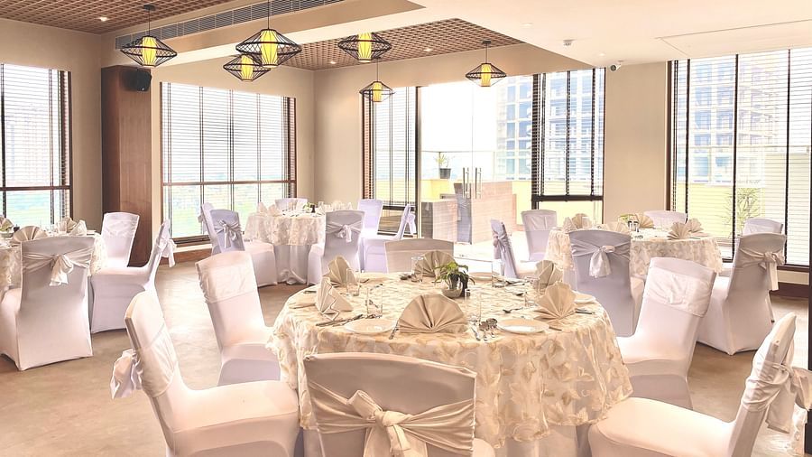 An image of a banquet hall with its seating arrangement and subtle decoration with lighting - Hideaway banquets & Lawns, Greater Noida