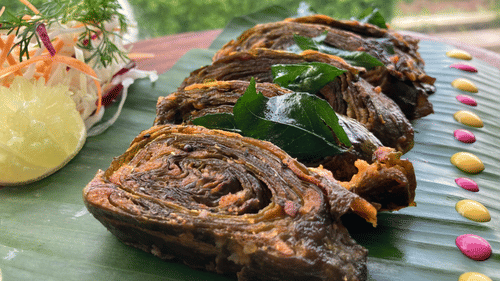A bunch of pathrode are arranged on a banana leaf with colourful chutneys