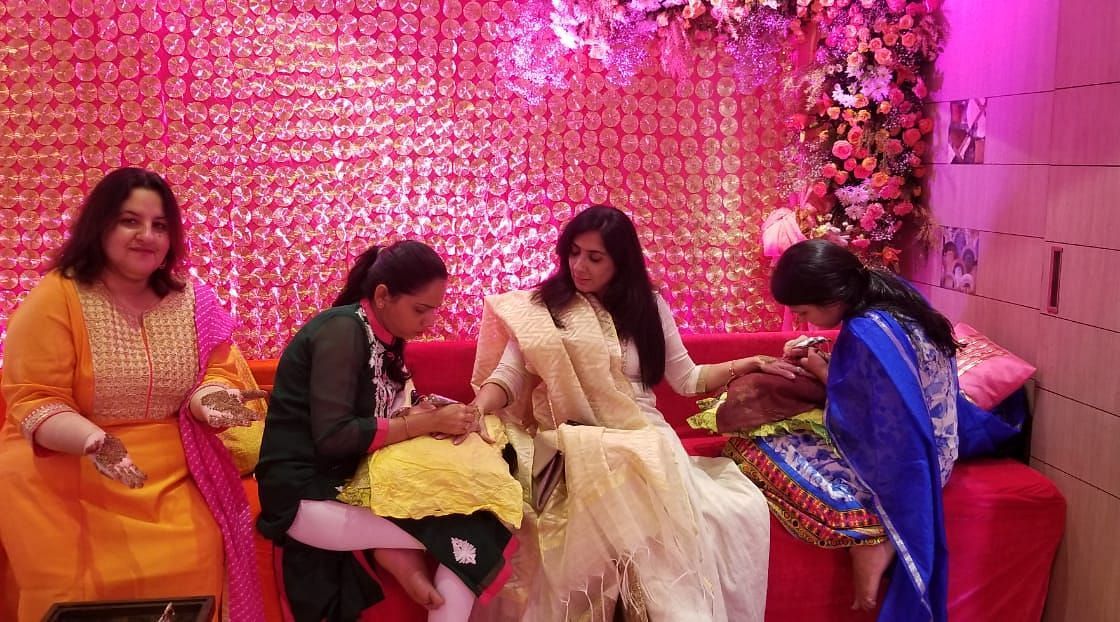 Two women applying mehendi on a ladys hand at at The Oriental Residency