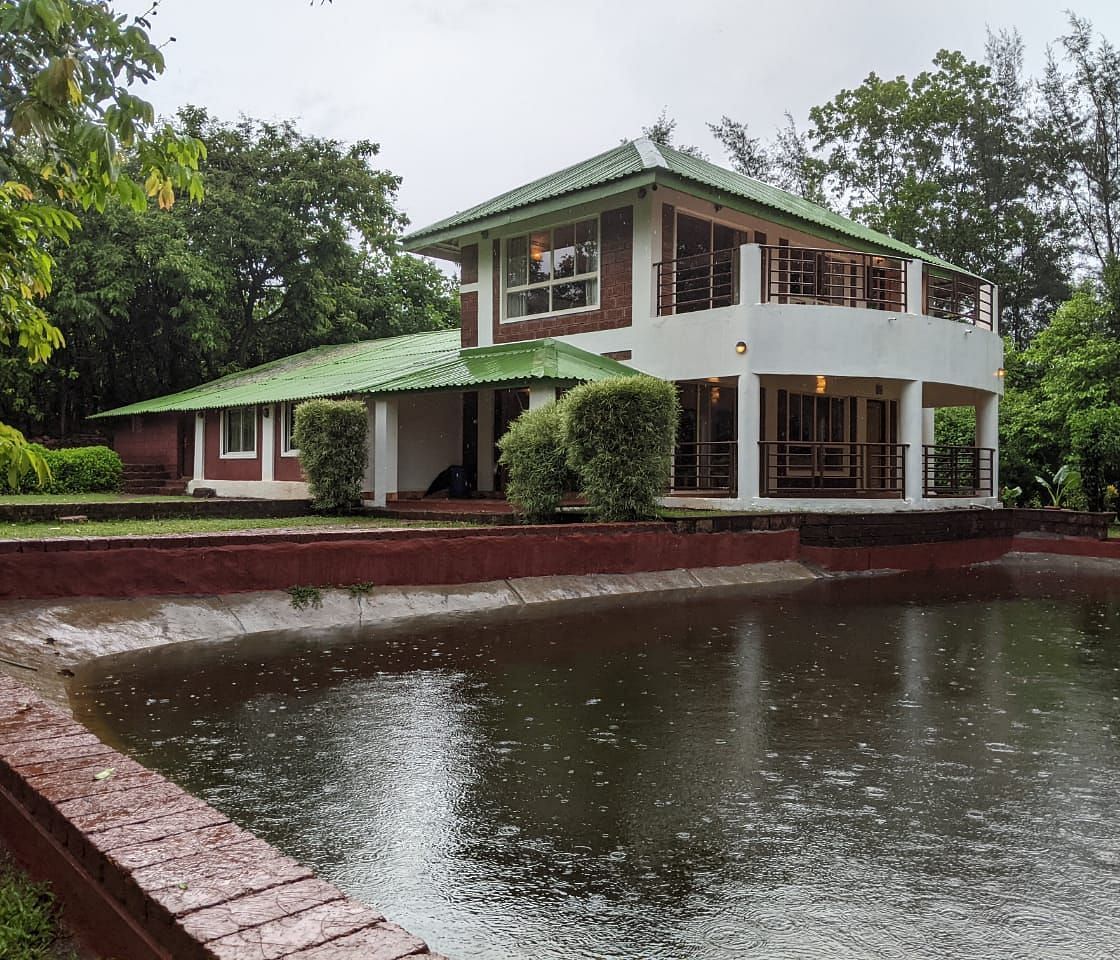 Facade view of The Conservancy Bungalow with a pond in the foreground and trees in the background.