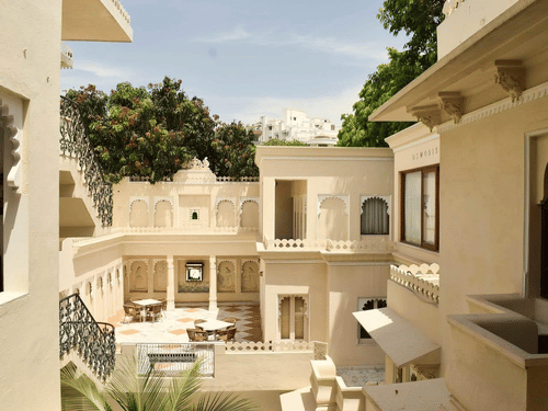 Courtyard with Rajasthani architecture, carved arches, staircase, and outdoor seating area at Ram Pratap Palace, Udaipur.