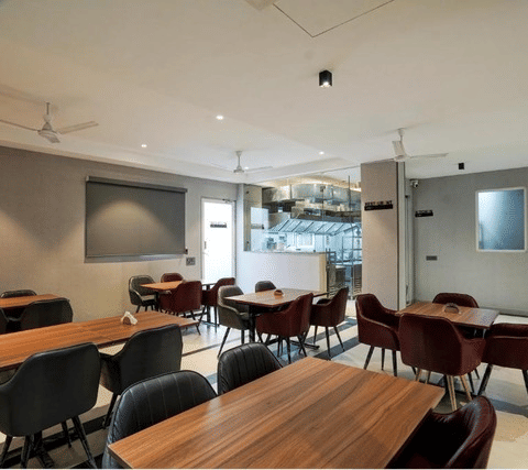 Dining area with wooden tables, chairs, and a modern interior at Ystays by Lime Tree Hotels, Greater Noida