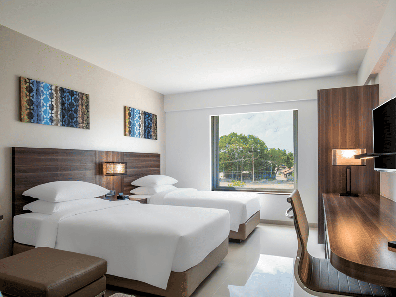Standard twin room decked with two beds, television and a working desk at The Residency Towers Rameswaram