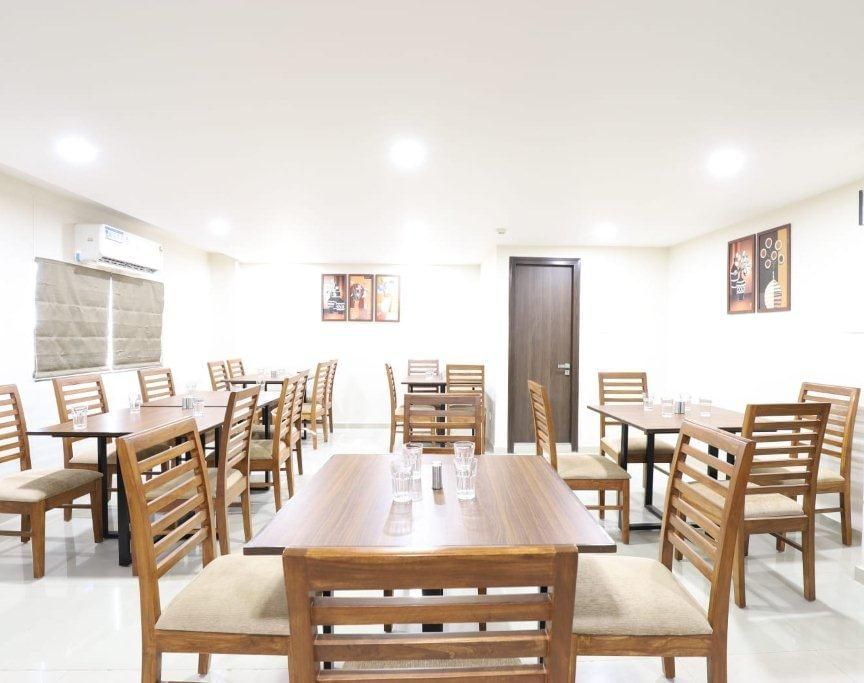 Side-angle view of a dining table with 2 chairs placed opposite to one another at Aranaya Restaurant at Pravasa Stay, Ahmedabad (Alba Premier).