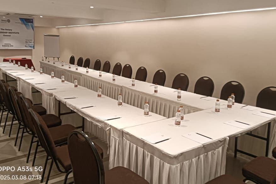 A long  u-shaped conference table with white tablecloths and chairs, prepared for a business event at Shilton Dee Cee.