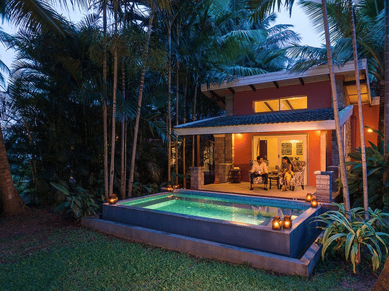 Evening view of The Residence at The Serai Kabini showing a covered patio, seating area, and a private swimming pool surrounded by trees.
