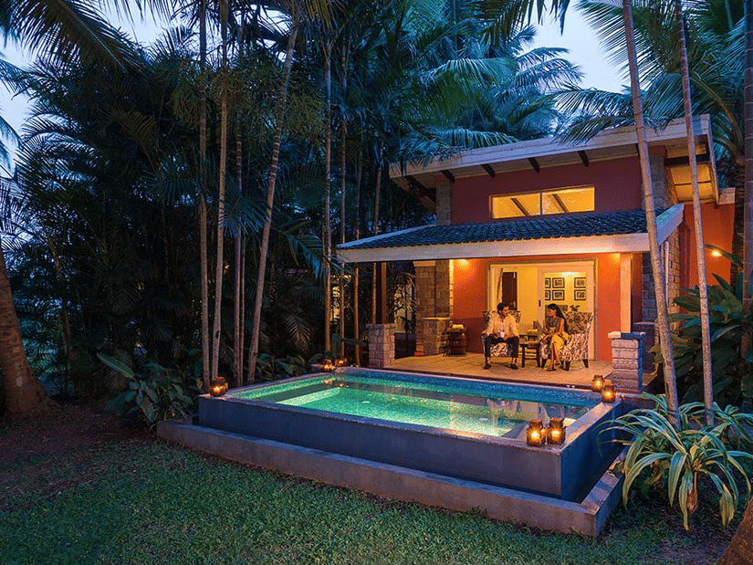 Evening view of The Residence at The Serai Kabini showing a covered patio, seating area, and a private swimming pool surrounded by trees.