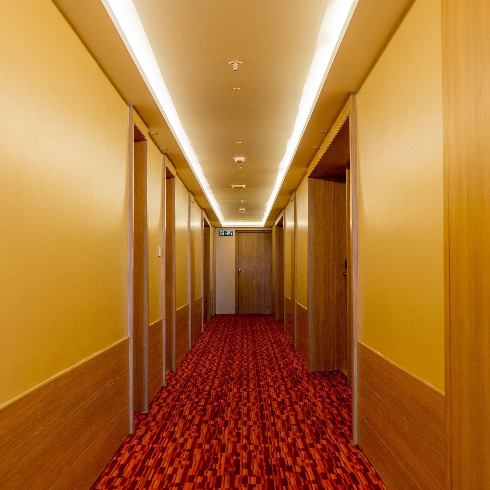 Long, well-lit corridor in a hotel with a red carpet | Gemini Continental