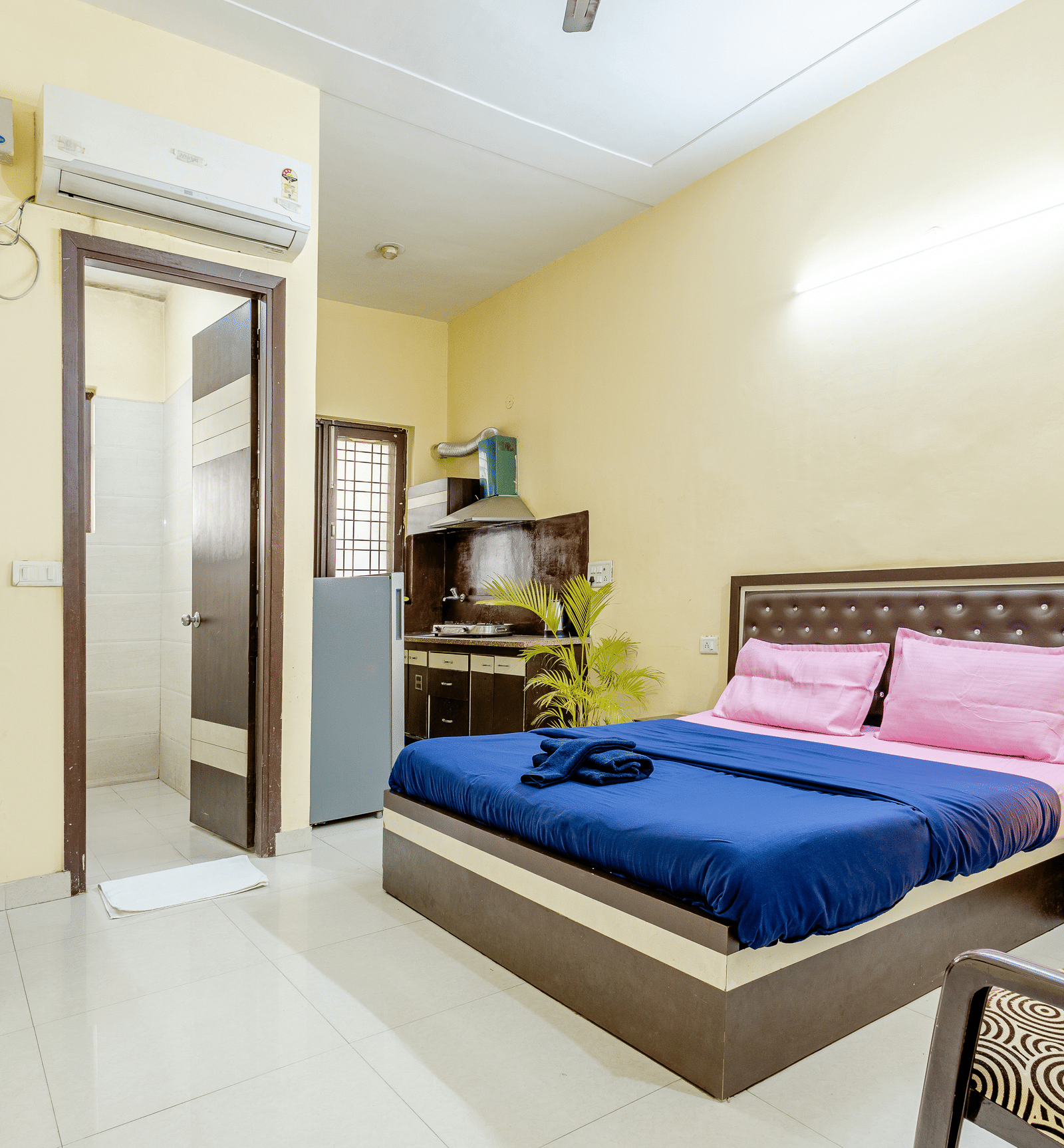 An image of a bedroom featuring a king size bed, a wardrobe, a bedside table, a seating area with chairs and tables,  and a small kitchenette - Lime Tree Studio Serviced Apartment, Gurgaon