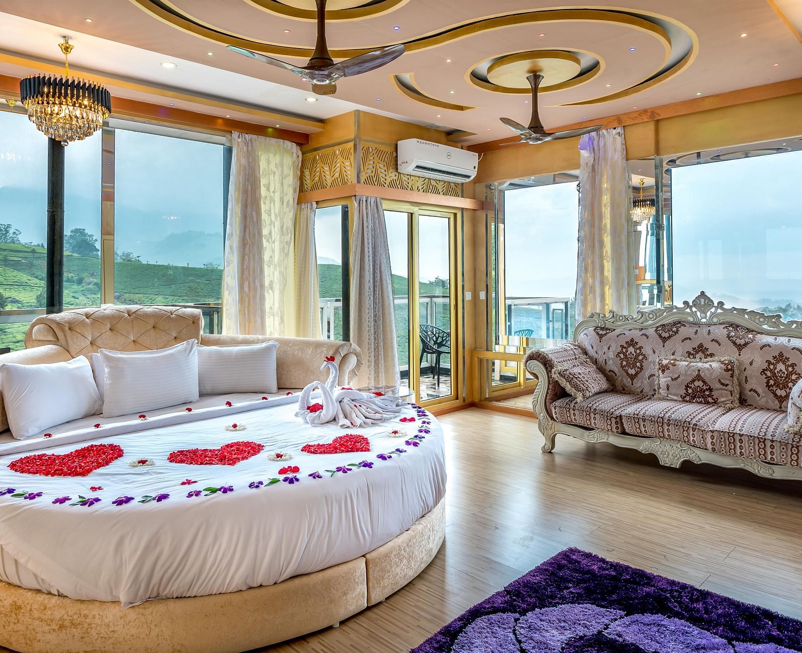 An image of a bedroom with round bed with cushions and next to it is a stylish sofa and the entire room is filled with natural light -  Parakkat hotel & resorts