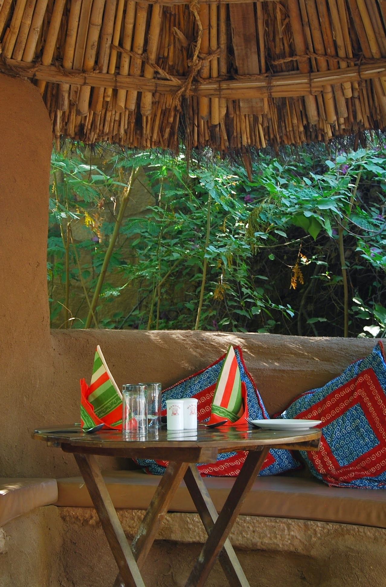 A close up shot of the seating arrangement of the Taasli Restaurant at Manvar Shergarh with a table laid out with crockery - Manvar Resort & Desert Camp