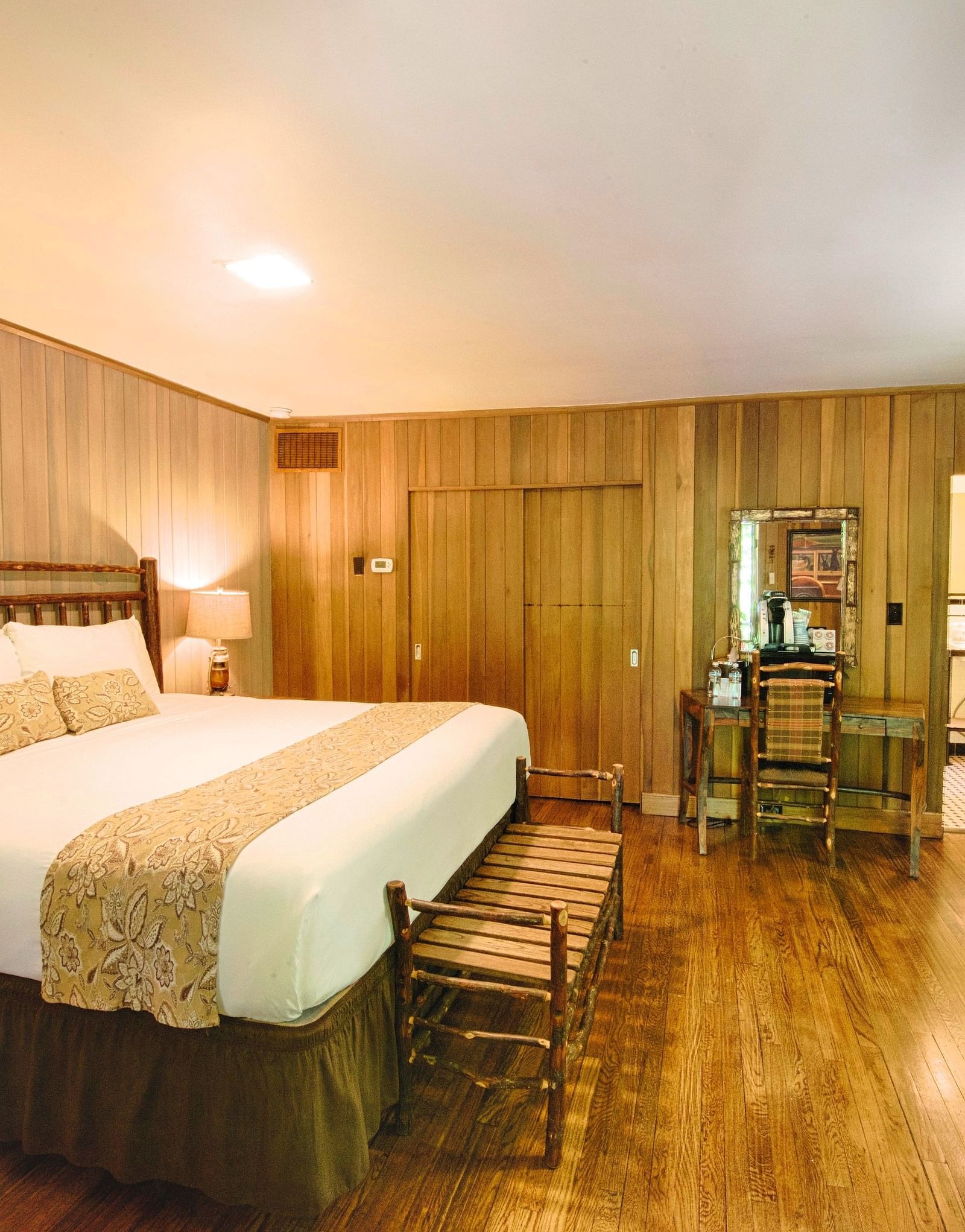 corner view image of a cozy bedroom with a double bed and wooden interiors along with a wall mounted television in the corner - Historic Tapoco Lodge
