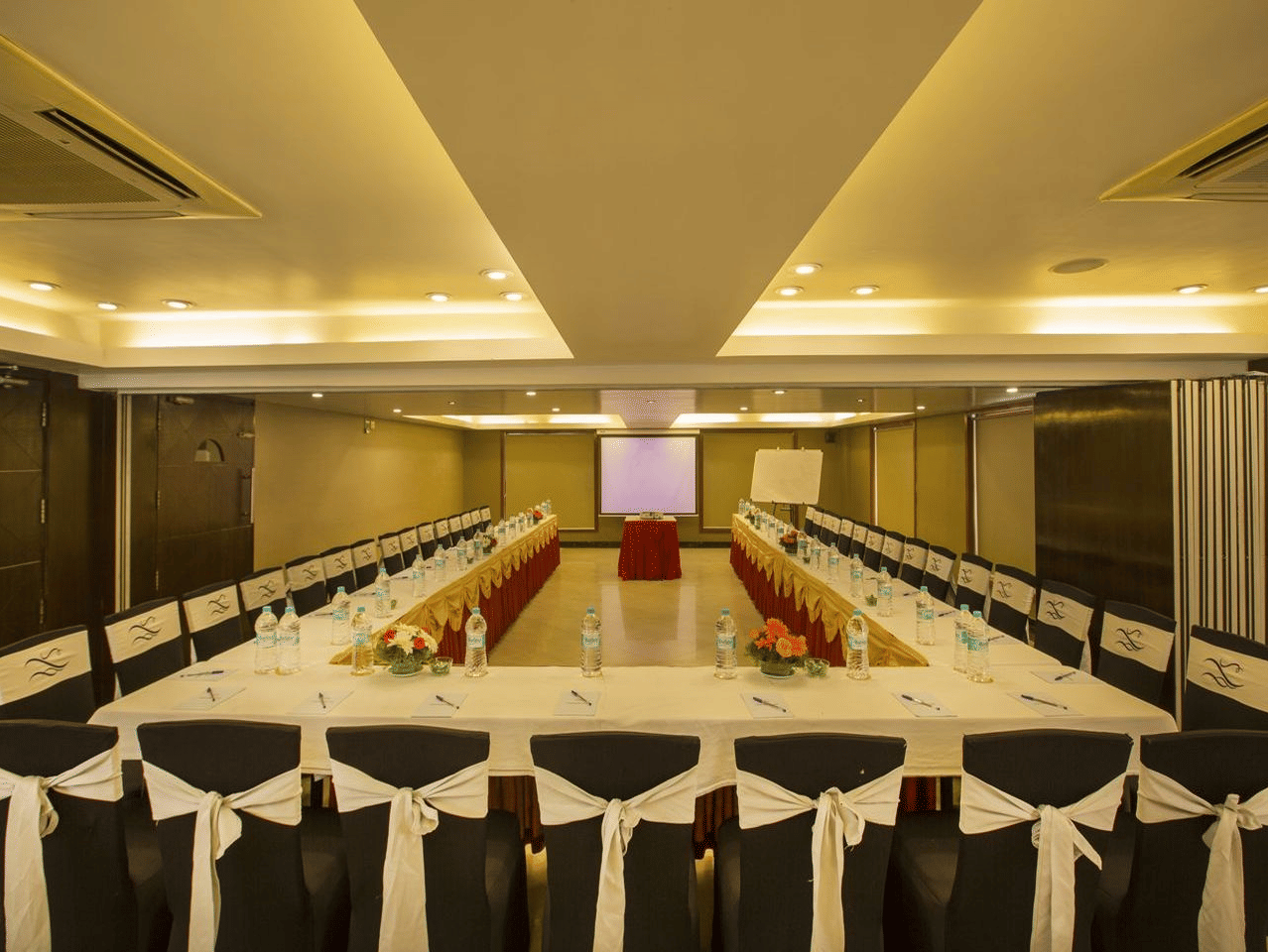 A meeting room with a long white table and black chairs - The Citrine