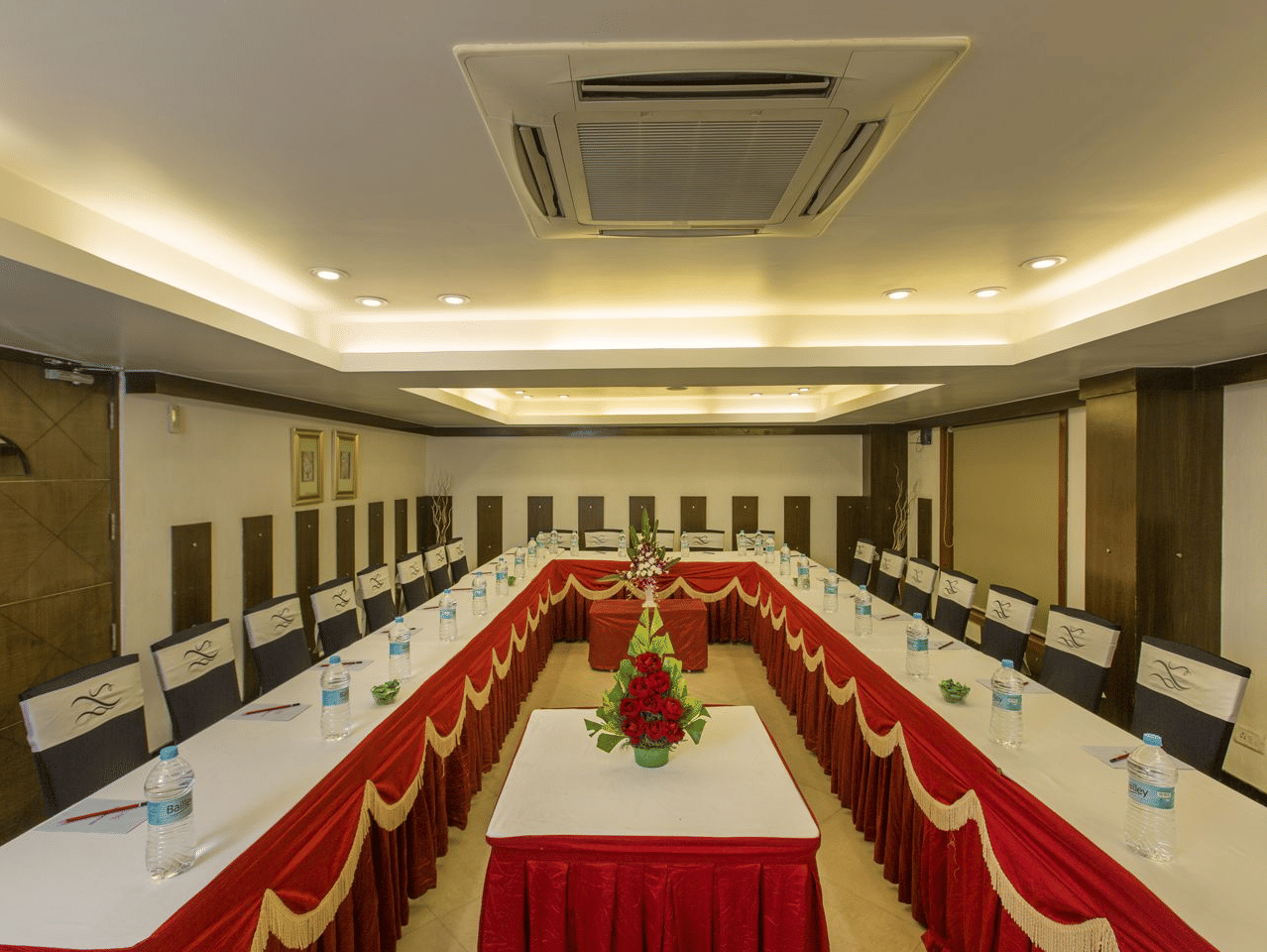 Large conference room with a long table, white chairs, and red runners - The Citrine