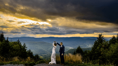 A newly wed couple posing for a photo-shoot with the forest in the backdrop on a cloudy day