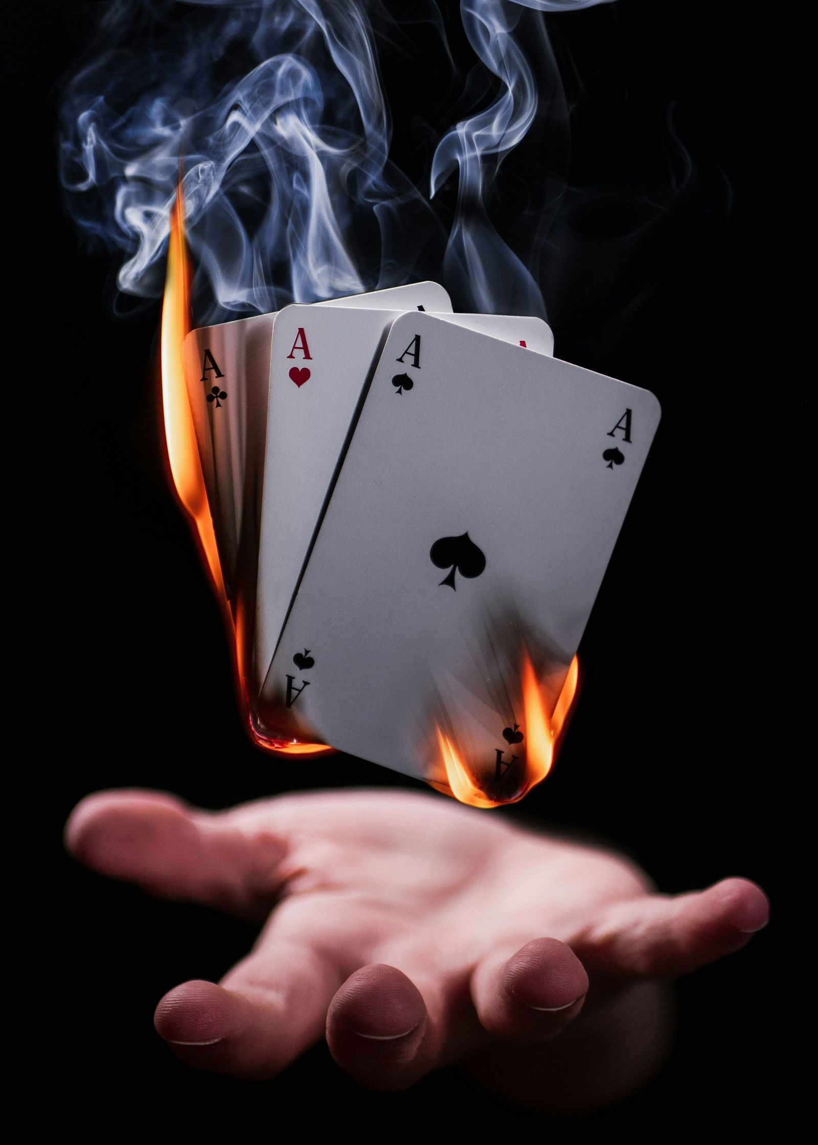burning playing cards with a magician hand below it