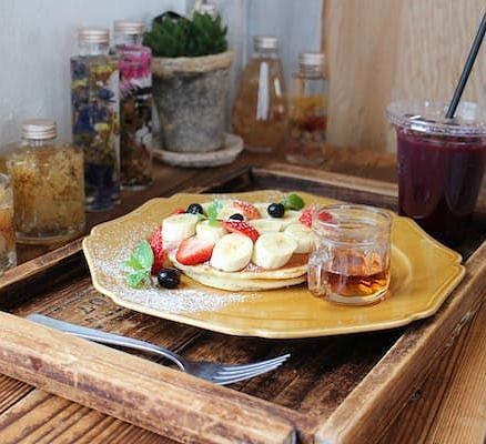 Breakfast tray filled with fruits and pancakes with a glass of juice
