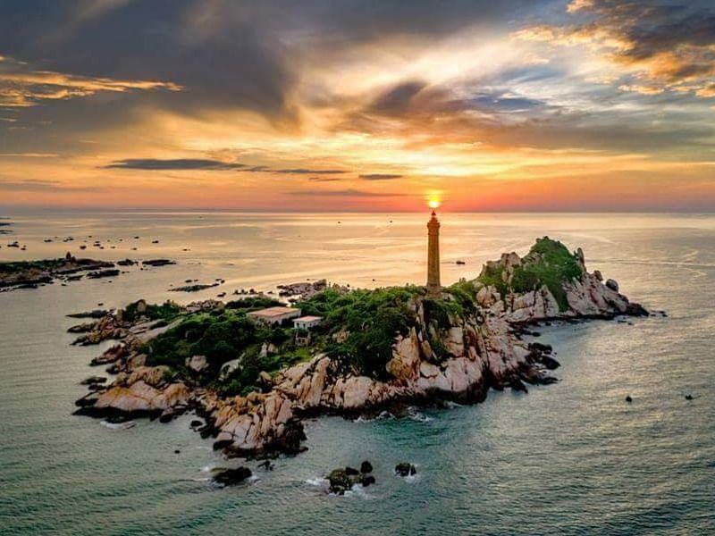 Aerial view of an island with a lighthouse during sunset.