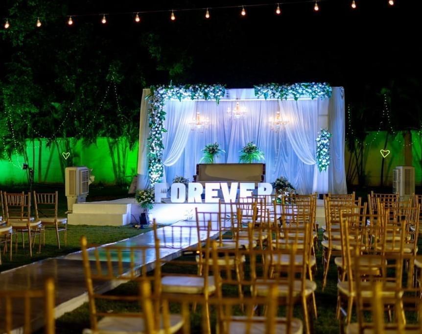 Evening view of outdoor seating facing a floral-lit stage with ‘FOREVER’ signage at Ilara Hotels & Spa, OMR, Chennai