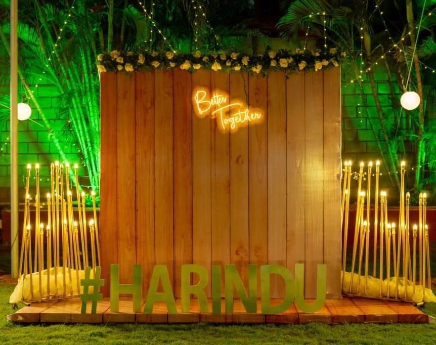 Rustic wooden photo backdrop with the couple's initials and name ‘Harindu’ in glowing lights at Ilara Hotels & Spa, OMR, Chennai