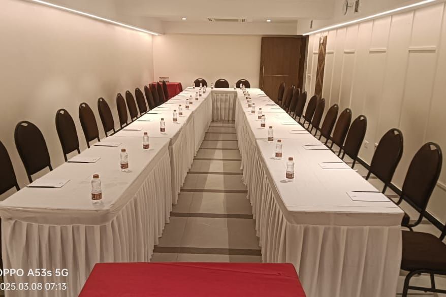 A u-shaped conference table with white tablecloths and chairs, ready for a large gathering at Shilton Dee Cee.
