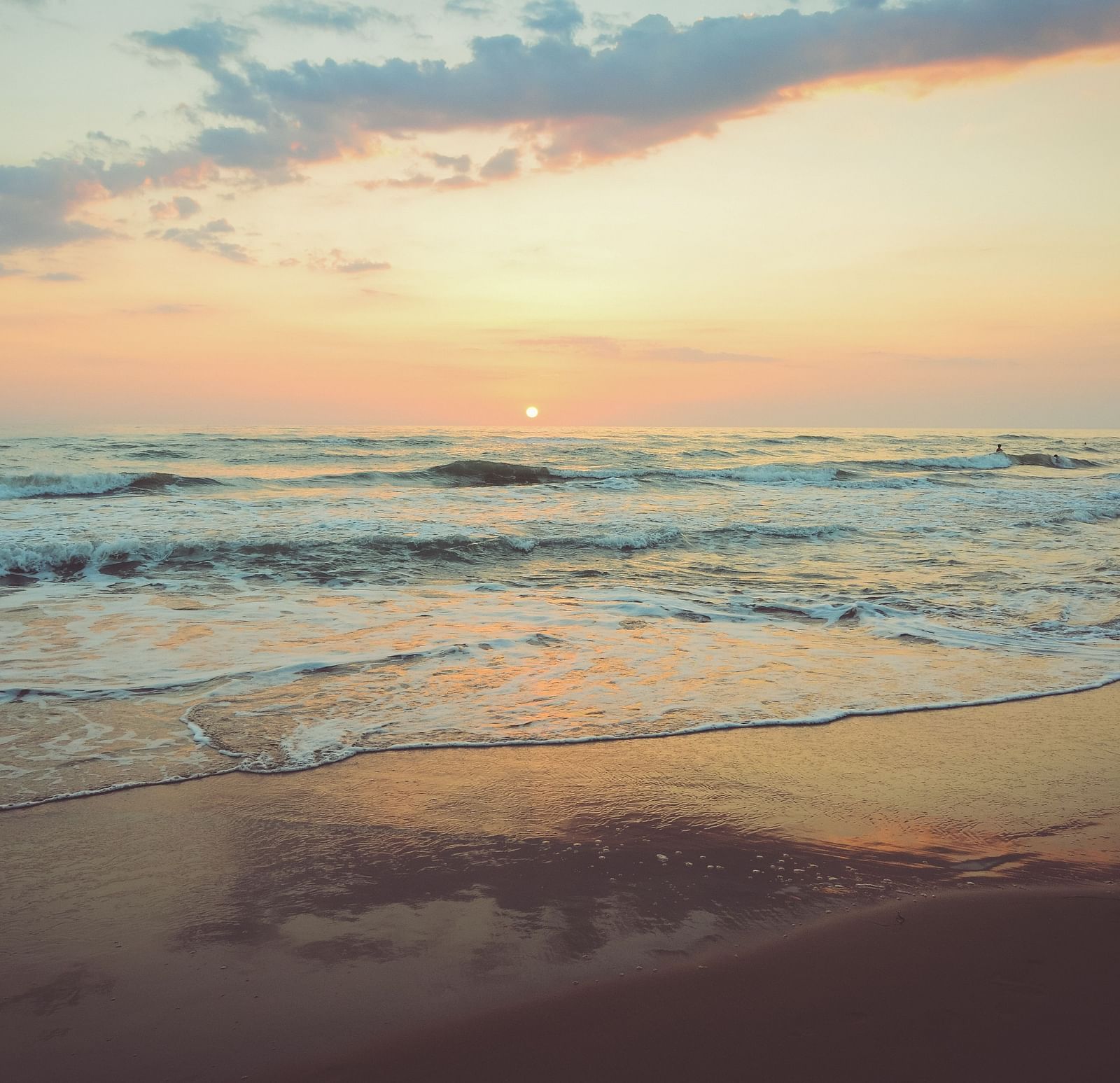 Waves overlapping on the beach with the setting sun in the background