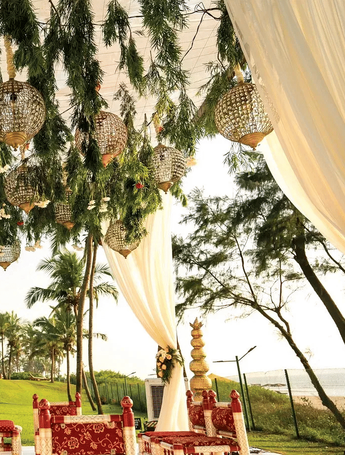 Elegant outdoor wedding ceremony setup with hanging basket lights and white draping at Caravela Beach Resort Goa