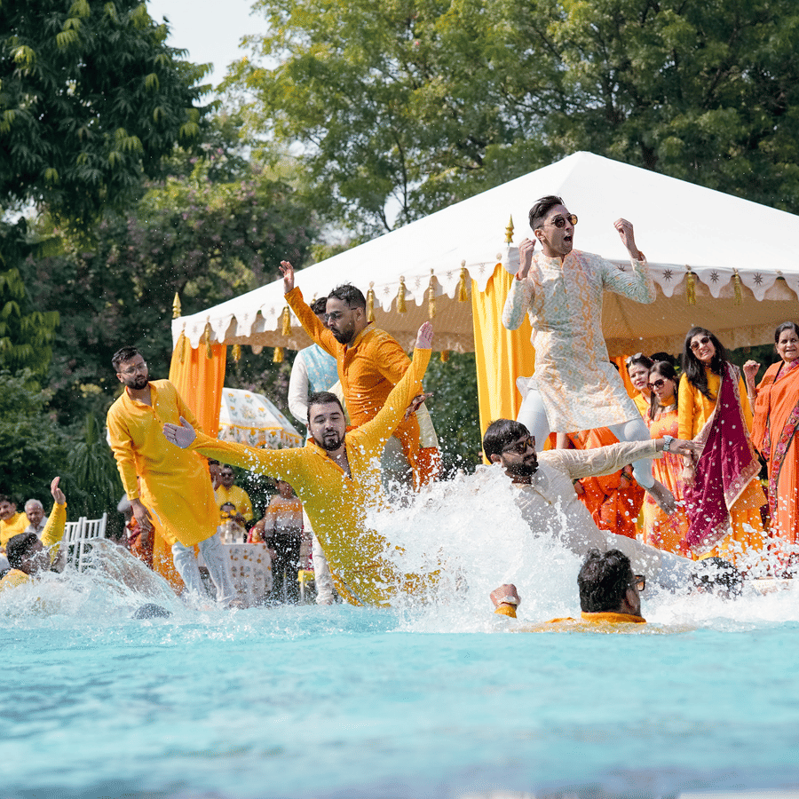 Joyful haldi ceremony with guests celebrating in a poolside setting.