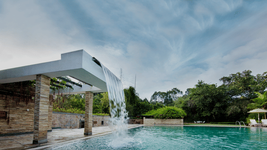 Luxury swimming pool with a modern waterfall structure at Amanvana Spa Resort in Coorg.