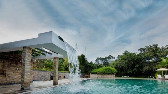 Luxurious pool with a modern waterfall feature and greenery around.