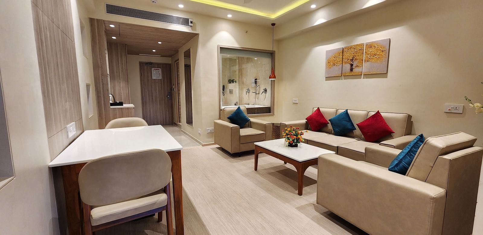 Spacious hotel suite with a work desk, comfortable seating area, and warm ambient lighting.