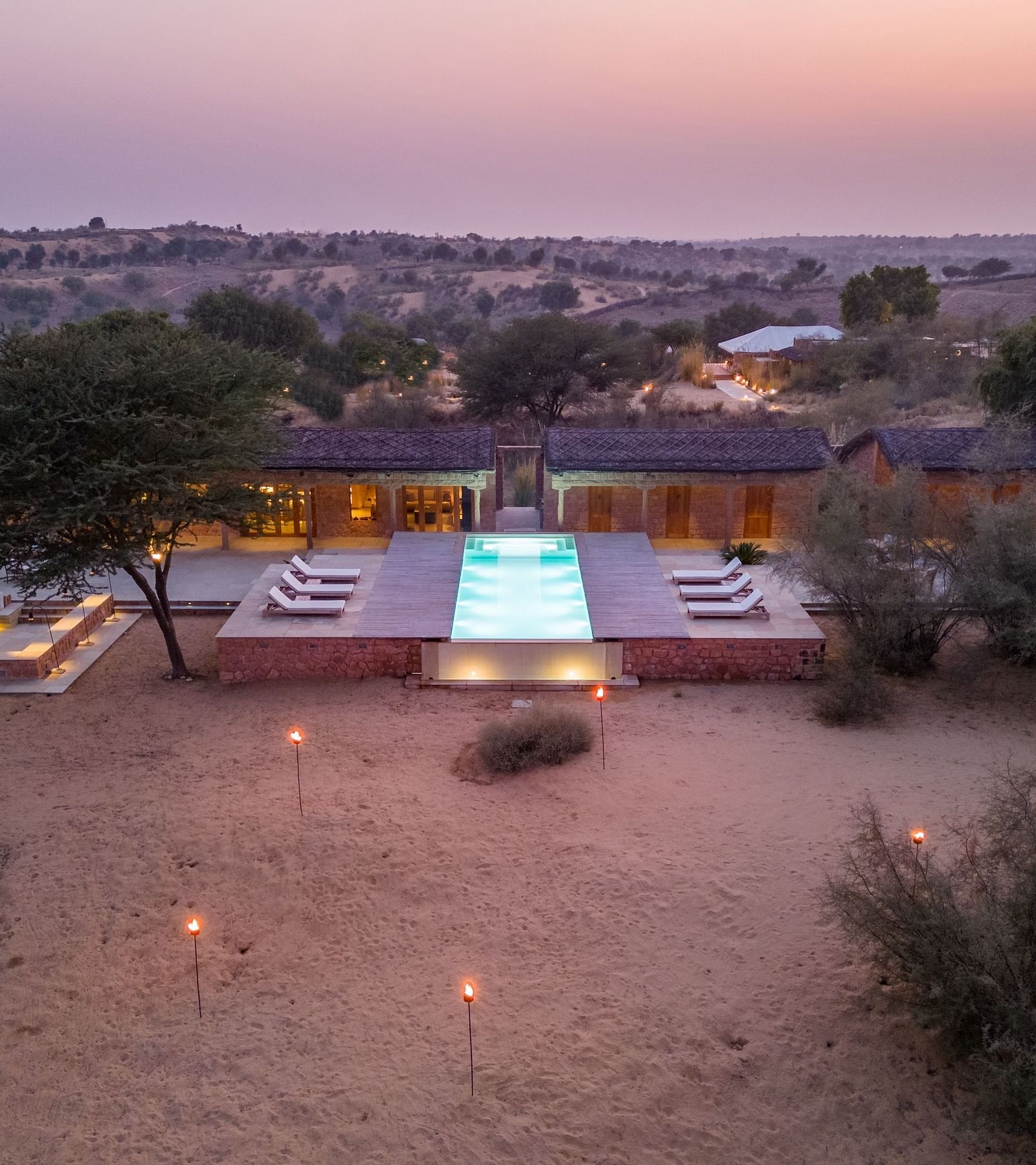 A well-lit path leads to a modern desert villa at twilight, highlighting the blend of luxury and nature - MANVAR Resort & Desert Camp