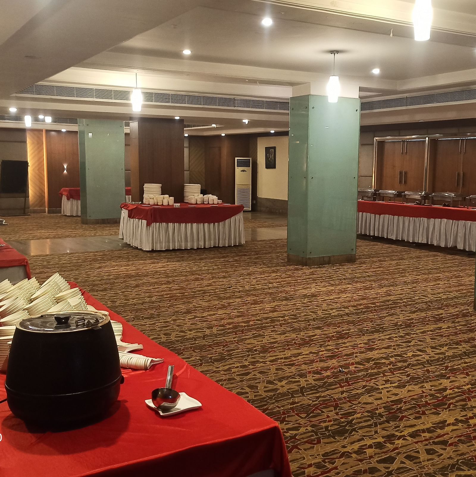 A warmly lit carpeted banquet hall of Lords Plaza Ankleshwar with buffet stations arranged along the sides of the room