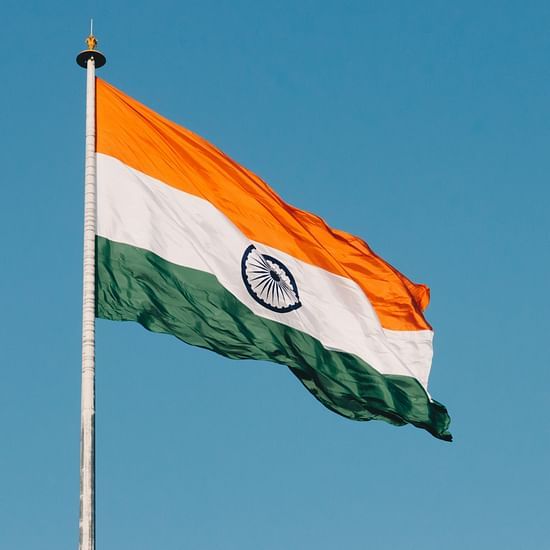 A far out view of the Indian Flag high on a pole with wind fluttering the flag