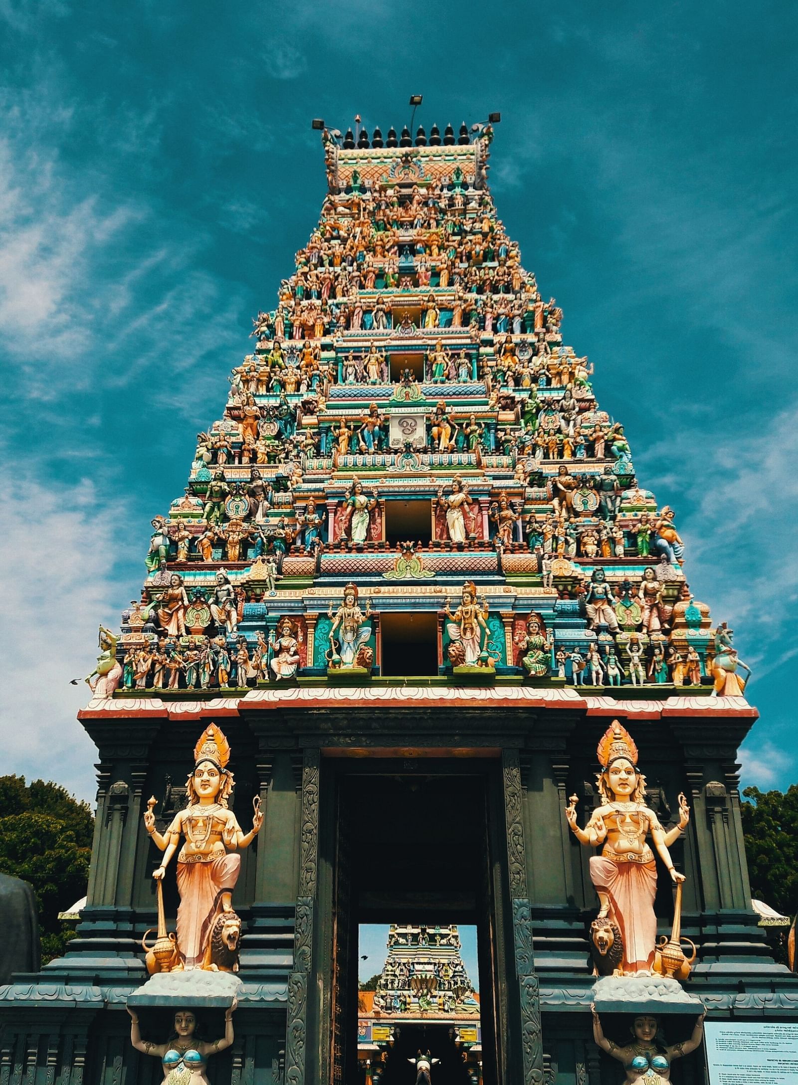 A temple with intricate carvings on its roof and two hindu deities on either side of the entrance