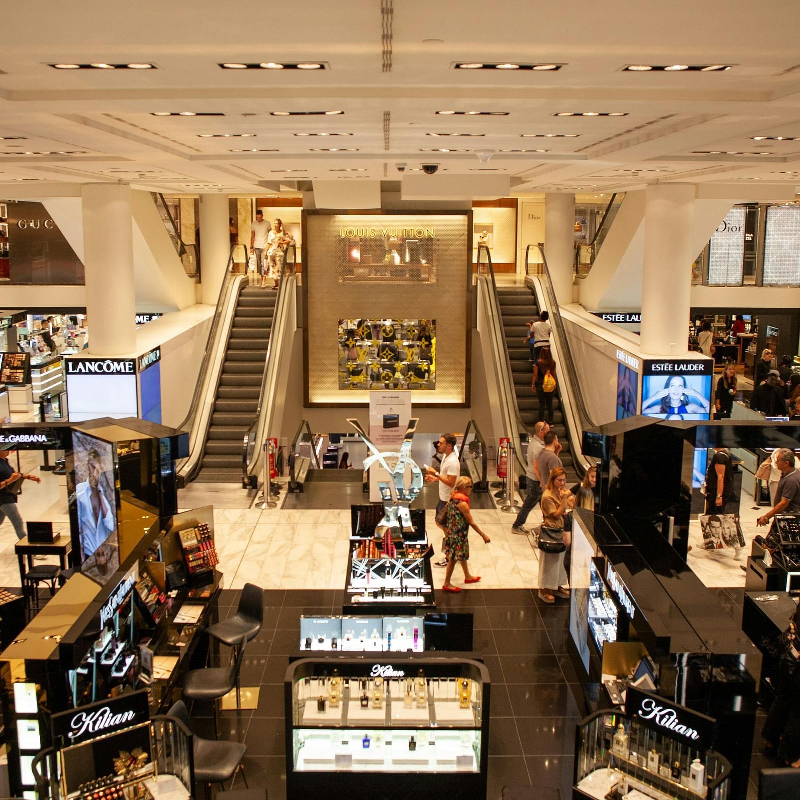 interior of a crowded shopping mall with escalators at the far end of the corridor