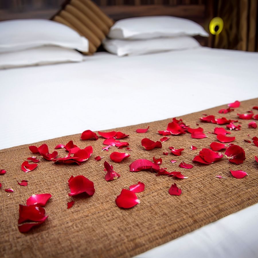 Adamo Resort Matheran - A close up view of the bed decorated with flower petals in Regent Room