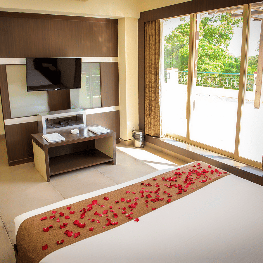 The bedroom of the Royal Suite with bed, TV, console and glass doors leading to the balcony.