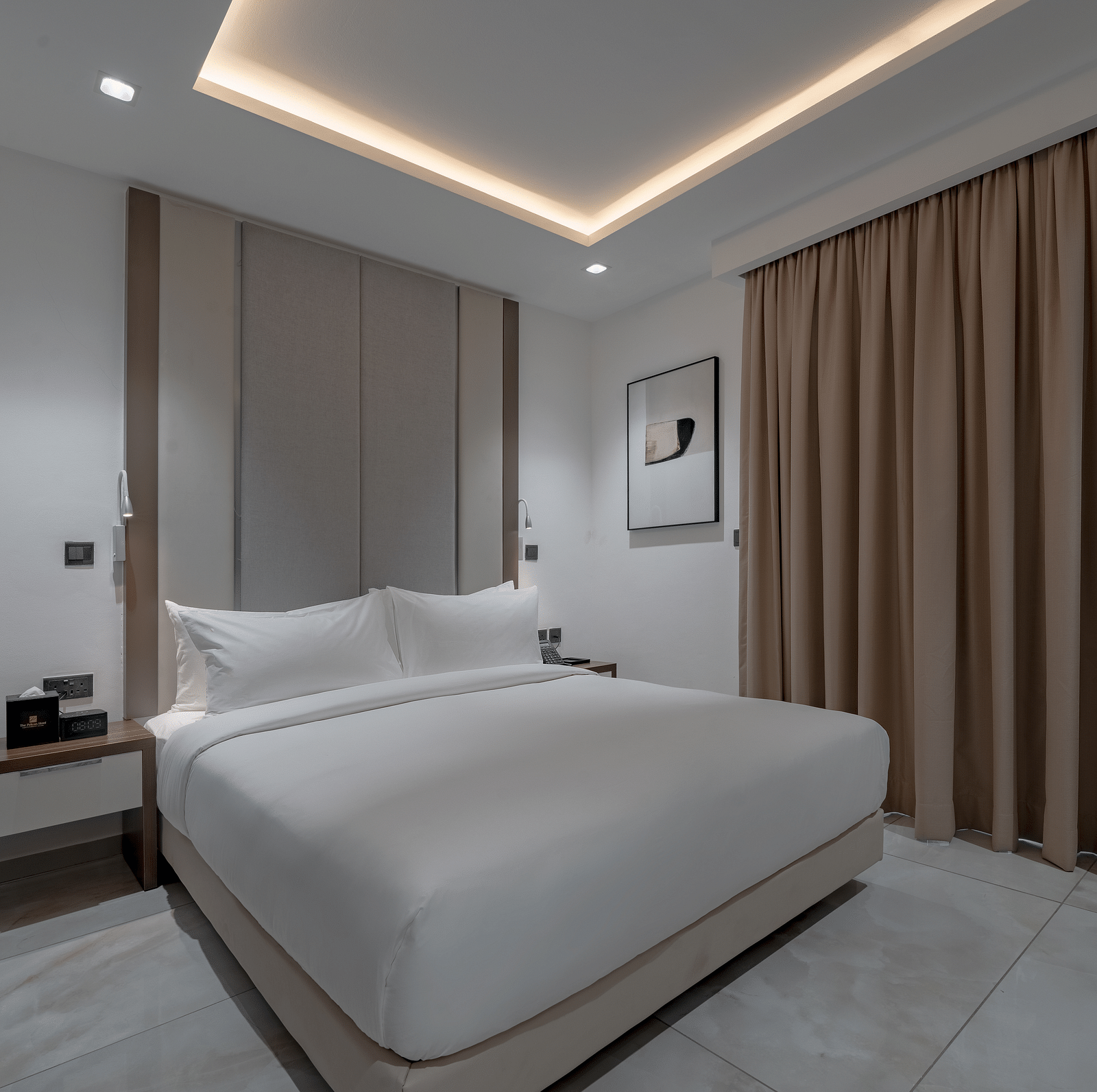 A well-lit Standard Room with a king size bed next to curtains. - The Pelican Hotel, Accra