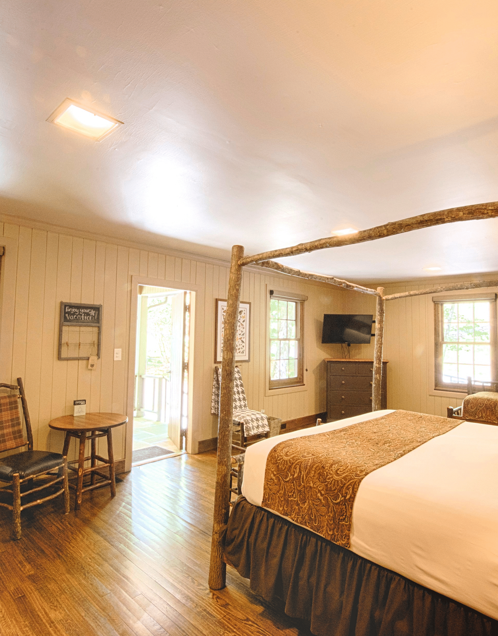 a room featuring an inviting double bed with the main door right in front of it along with a chair and a coffee table besides it - Historic Tapoco Lodge