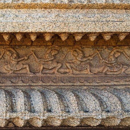 Detailed stone carving of dancing figures on temple wall.