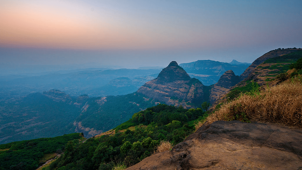 image of the serene landscape taken from a hilly elevation featuring a few hills during the dusk in Lonavala.