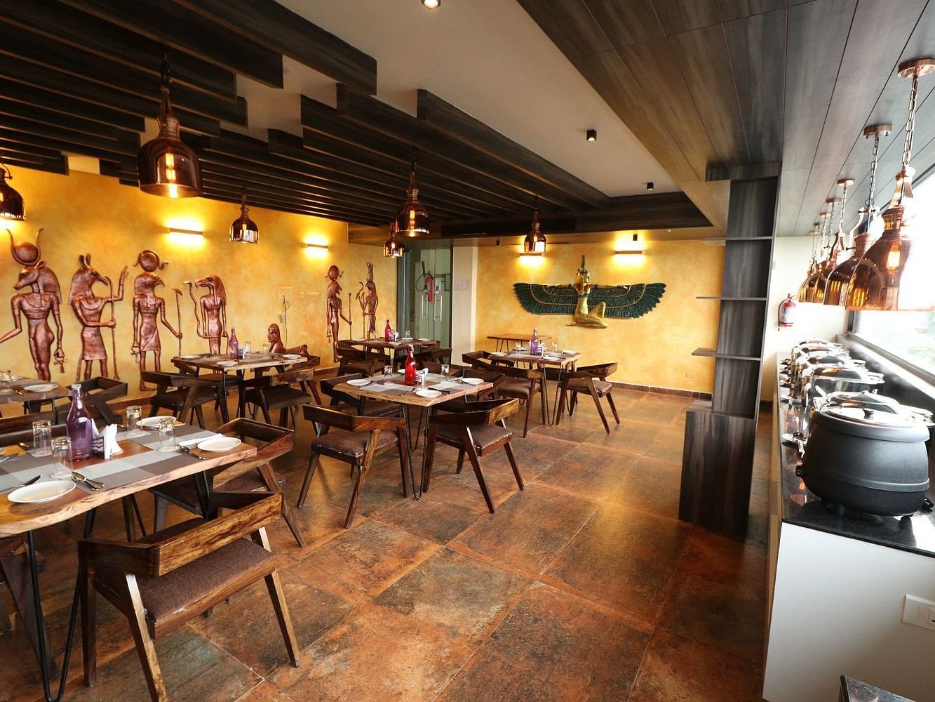 A stylish restaurant interior with multiple dining tables, chairs, ambient lighting, and warm wooden accents - Sea Hills Hotels, Sri Vijayapuram (Port Blair)