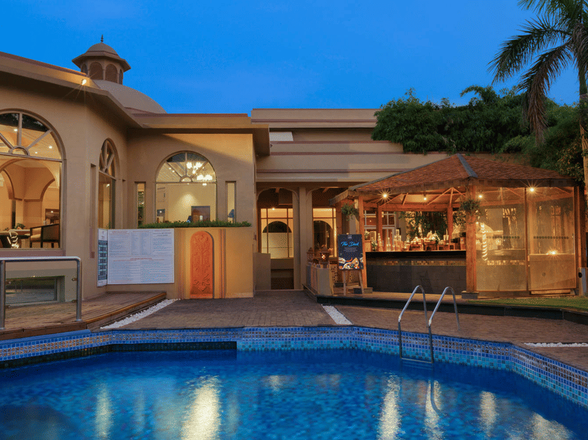 Facade of Heritage Village Resorts and Spa, Manesar with Rajasthani architecture and a pool in the foreground.