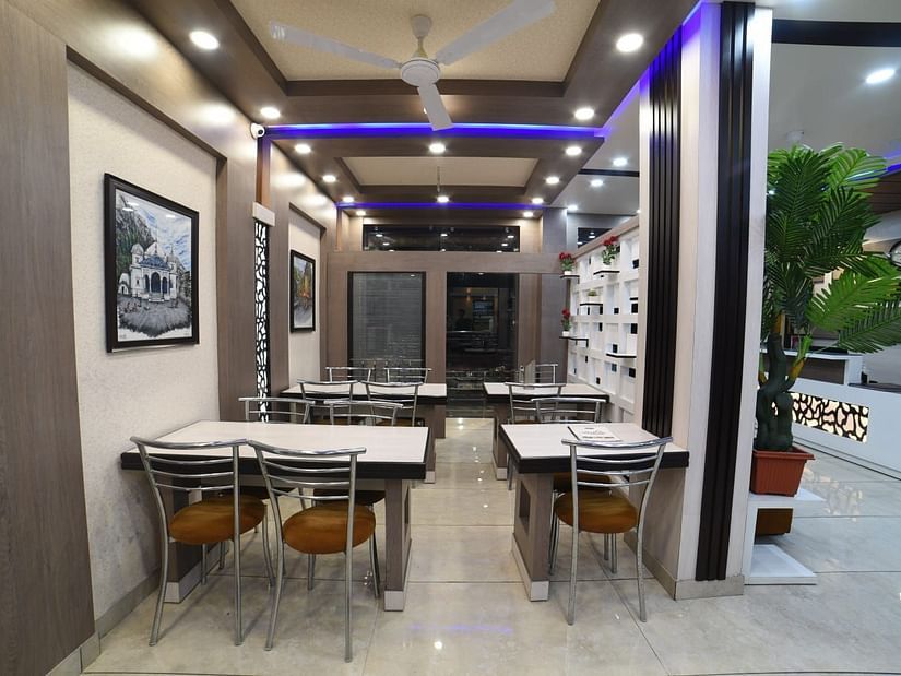 Restaurant with white tables and chairs at Hotel Panchvati Inn