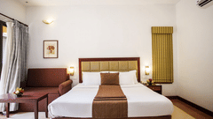 An overview of a room with a double bed and a sofa next to it inside one of the rooms - Abad Green Forest, Thekkady.