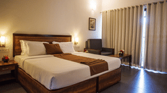 An overview of a room with a king bed, side lamps and tables at Abad Green Forest, Thekkady - The perfect Forest Stay in Kerala.