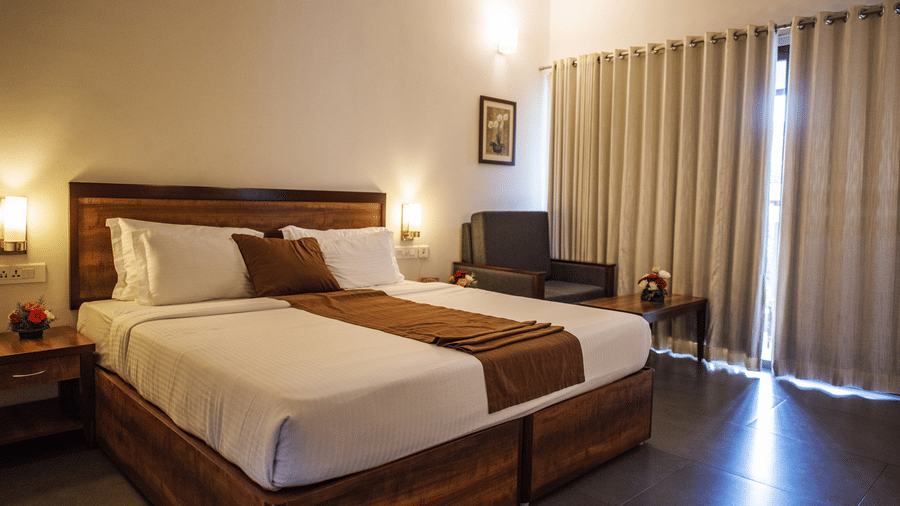 An overview of a room with a king bed, side lamps and tables at Abad Green Forest, Thekkady - The perfect Forest Stay in Kerala.